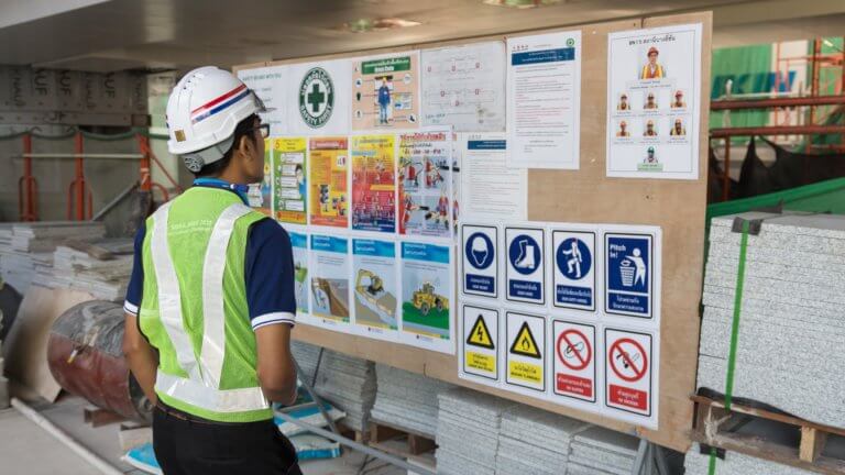 The engineer reading notice board of workplace health and safety policy before working in construction site